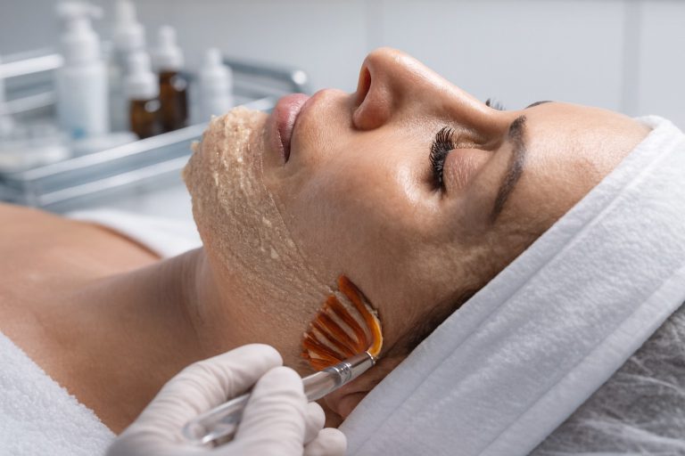 Therapist applying an exfoliating mask with a brush during a deep pore cleansing facial